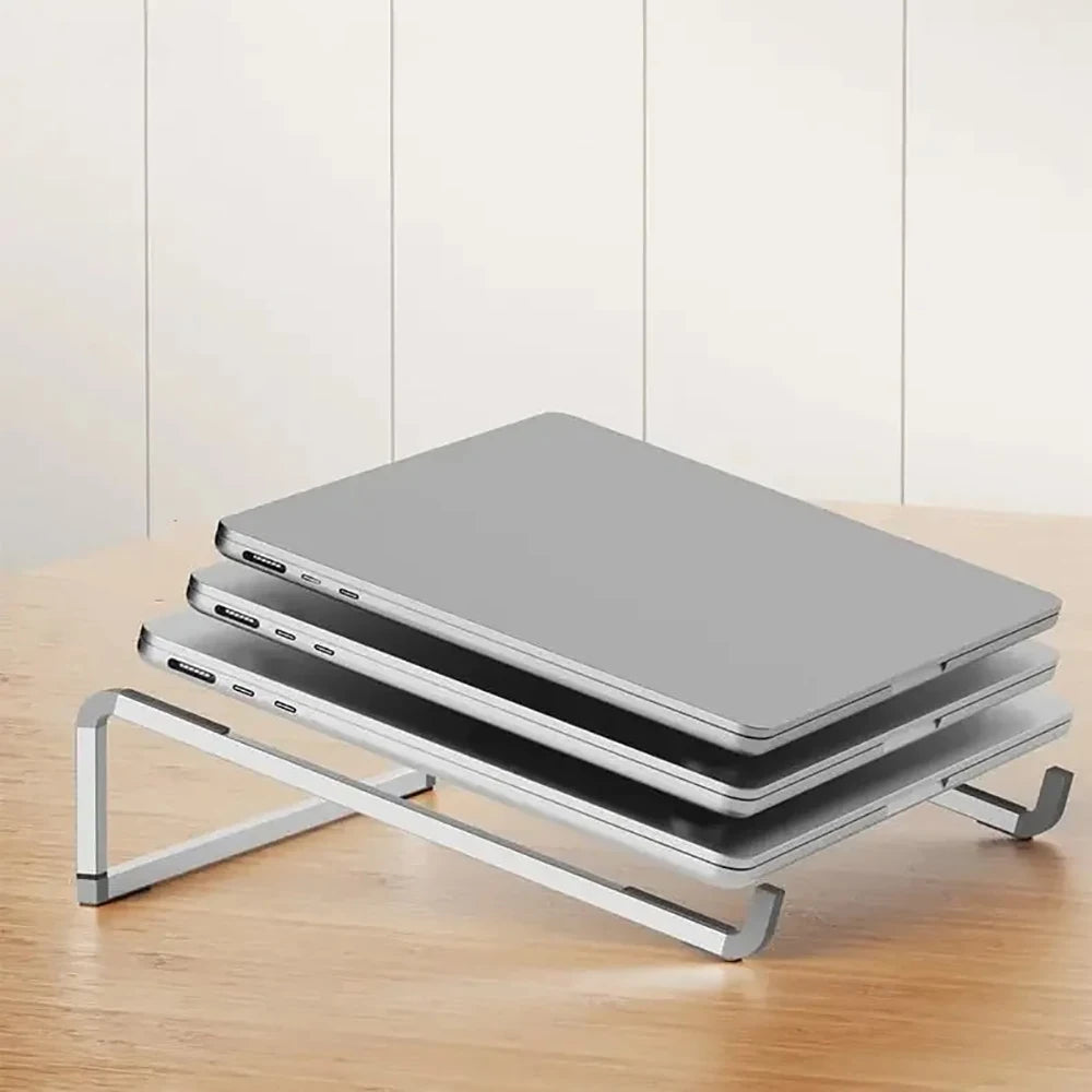 A silver foldable aluminum laptop stand holding a gray laptop on a wooden surface.