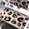 A large leopard print desk pad is displayed on a white desk next to a digital clock and a computer monitor.