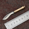 A polished brass fixed blade knife is shown next to a ruler, highlighting its size and craftsmanship.