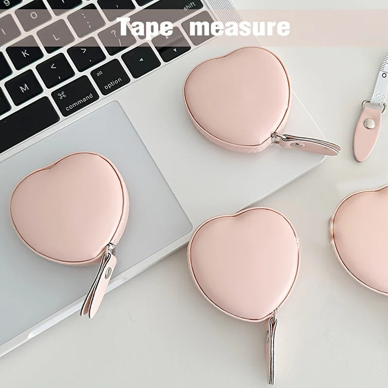 A pink PU leather measuring tape with a heart-shaped clip is shown next to a laptop keyboard.