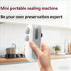 A hand holds a white and gray mini portable sealing machine device against a kitchen countertop.