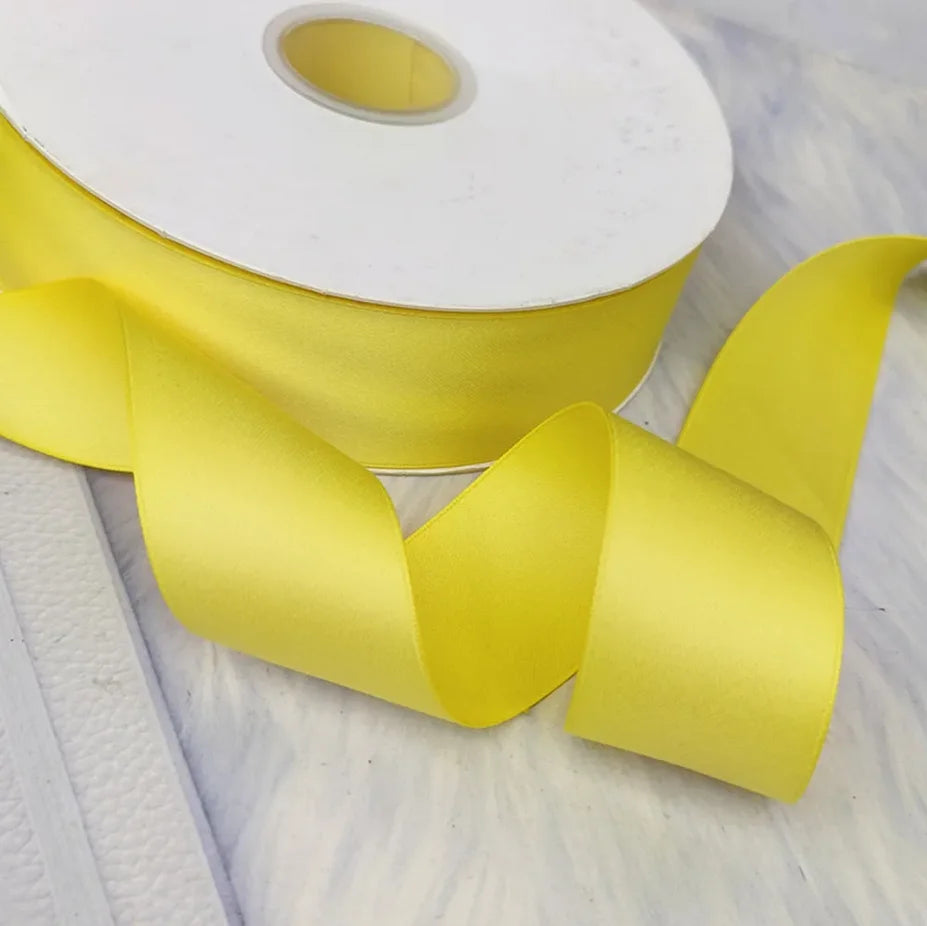Yellow matte finish satin ribbon rolled on a white core, shown in a close-up.