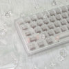 Nahaufnahme klarer und getönter PC-Tastenkappen für eine mechanische Tastatur auf weißem Stoff mit Eiskristallen