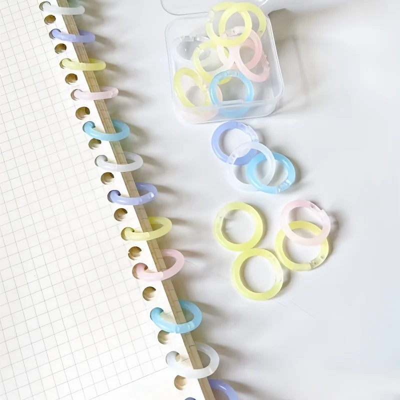 A collection of colorful reusable plastic binding rings in various shades of yellow, pink, and blue are displayed on a white 