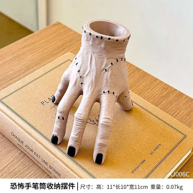 A light beige resin palm hand decoration with black studs, displayed on a wooden surface.
