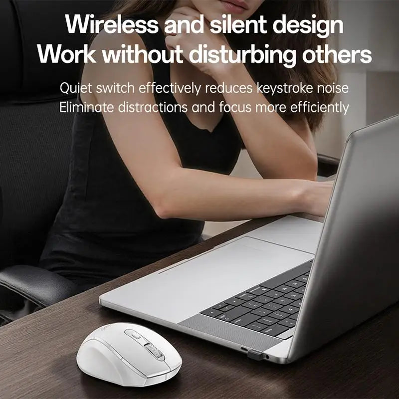 A wireless ergonomic mouse is shown next to a laptop, with a person in the background working.