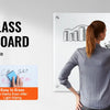 A woman writes on a magnetic glass dry erase board showing various diagrams and graphs.