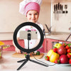 A smiling child wearing a chef hat is using an LED ring light with a tripod stand for photography or streaming.