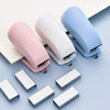 A set of light pink and blue compact mini staplers with staples scattered on a white grid background.