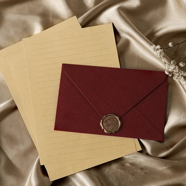 Un ensemble d'enveloppes en papier de lin brun rétro avec une enveloppe en velours marron featuring un pendentif or.