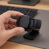 A hand holds a black privacy lens cover for a webcam, demonstrating its compact design.