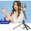 A woman is using an extendable selfie stick tripod for live video streaming.