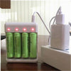 A white battery charger device with four green cells is shown next to a white power adapter.