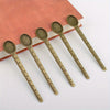 Five vintage brass straight rulers with minimalist design resting on a reddish-brown book.