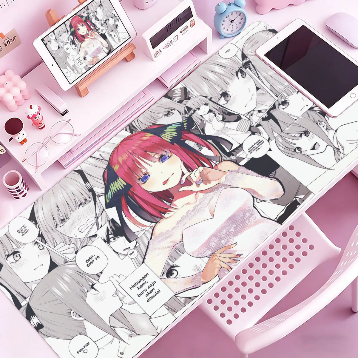 A pink mouse pad featuring anime characters and illustrations is displayed on a desk.