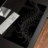 A black gaming mouse pad featuring a detailed silver gothic centipede design and an attached white keyboard.
