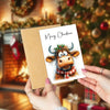 A set of 12 adorable highland cow greeting cards featuring a portrait of a cow with antlers and a festive wreath.