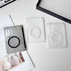 Clear silicone phone cases and a black case lying on a white surface next to a notebook.