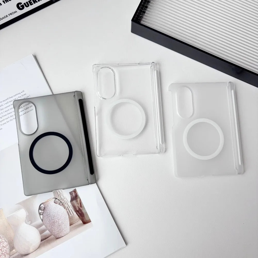 Clear silicone phone cases and a black case lying on a white surface next to a notebook.