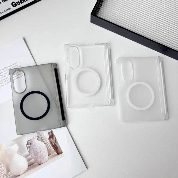 Clear silicone phone cases and a black case lying on a white surface next to a notebook.