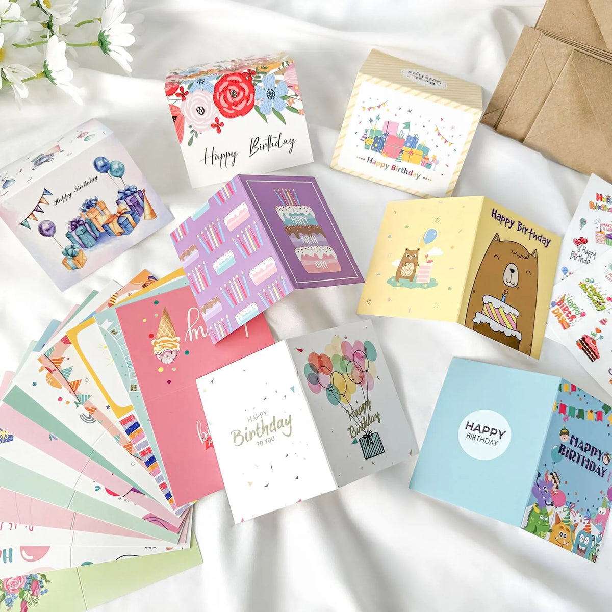 Eine Sammlung farbenfroher handgeschriebener Geburtstagskarten in verschiedenen Designs und Farben auf einer weißen Oberfläch