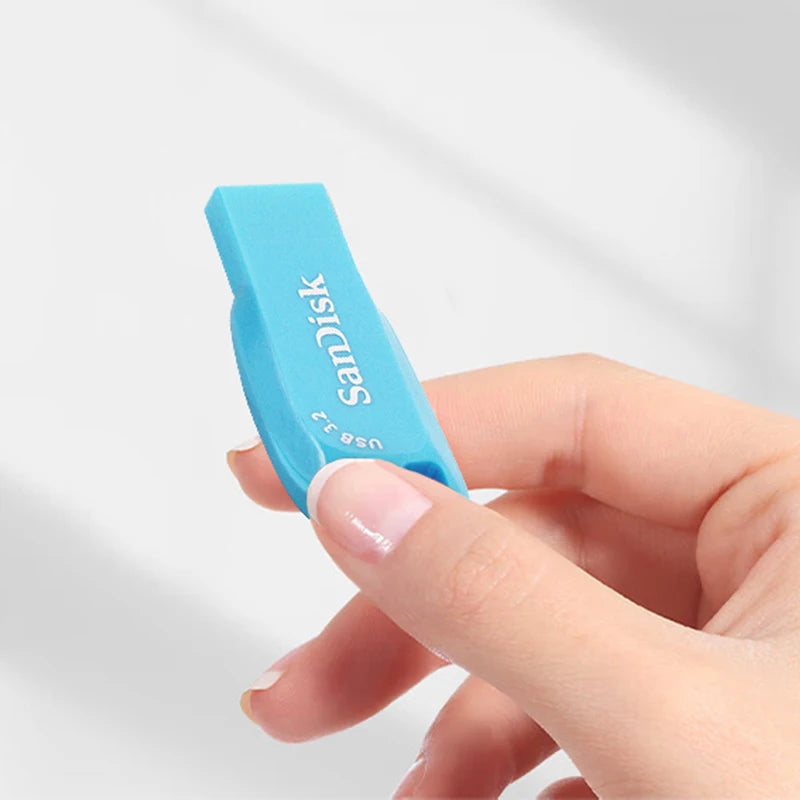 A hand holds a light blue SanDisk Ultra Shift USB 3.2 flash drive with the USB 3.2 connector visible.