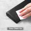 A hand is placing a white cleaning cloth onto a black ergonomic memory foam keyboard wrist rest.