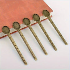 Five vintage brass straight rulers with minimalist design resting on a reddish-brown book.