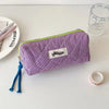 Purple checkered pencil case with a lime green trim resting on a white surface.