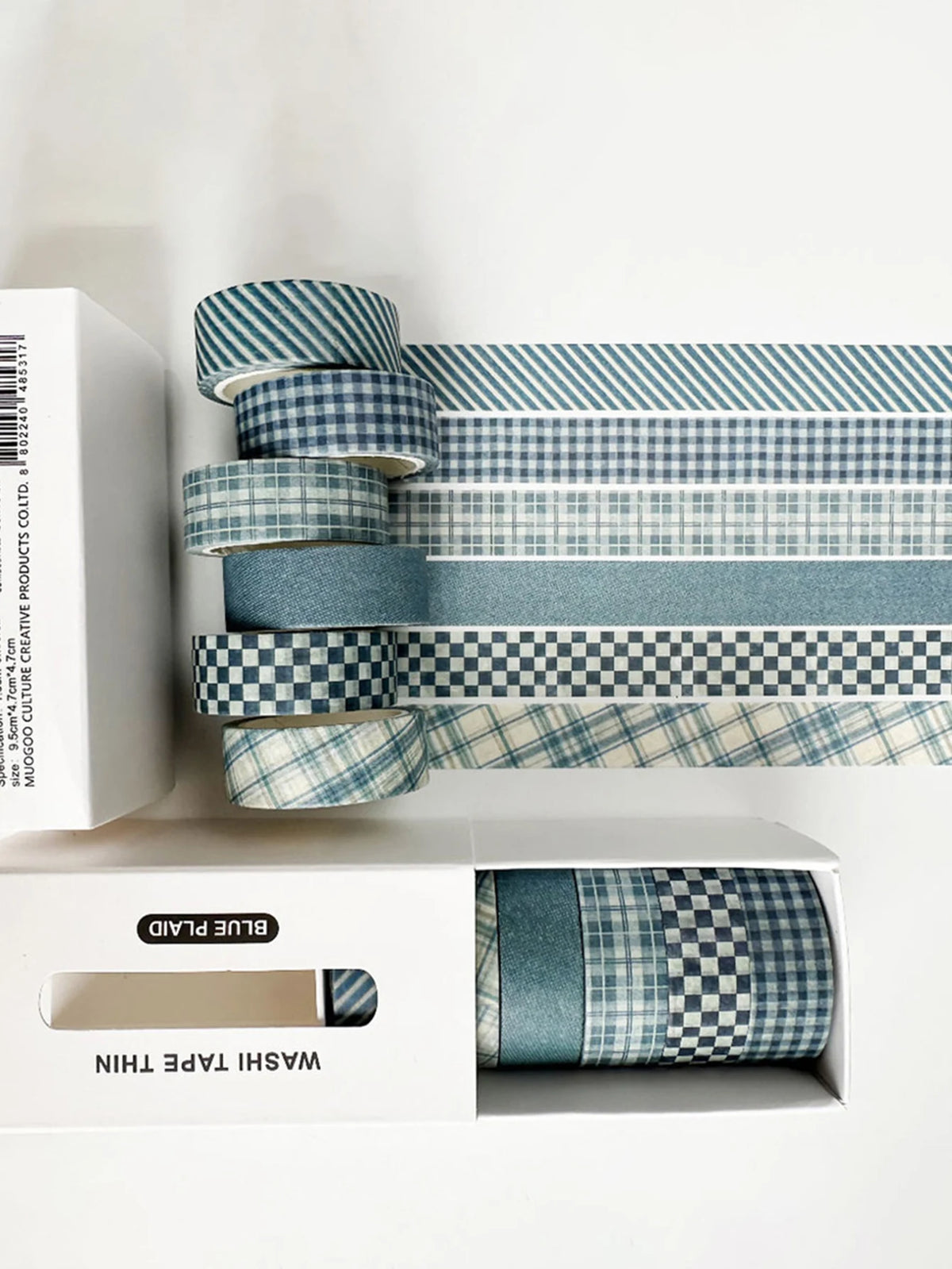 A set of six rolls of blue plaid washi tape in various patterns, including grid and polka dot designs, displayed in a white b