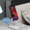 A white phone holder stand is shown next to an iPhone, designed to allow the phone to play while charging.