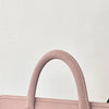 A close-up of a pink laptop sleeve with a curved handle, made of protective PU material.