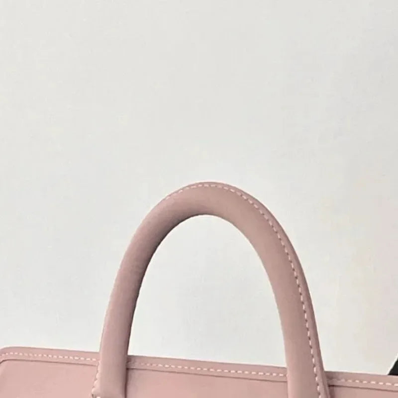 A close-up of a pink laptop sleeve with a curved handle, made of protective PU material.