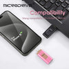 A black iPhone 15 smartphone next to a black computer keyboard and a pink USB flash drive.
