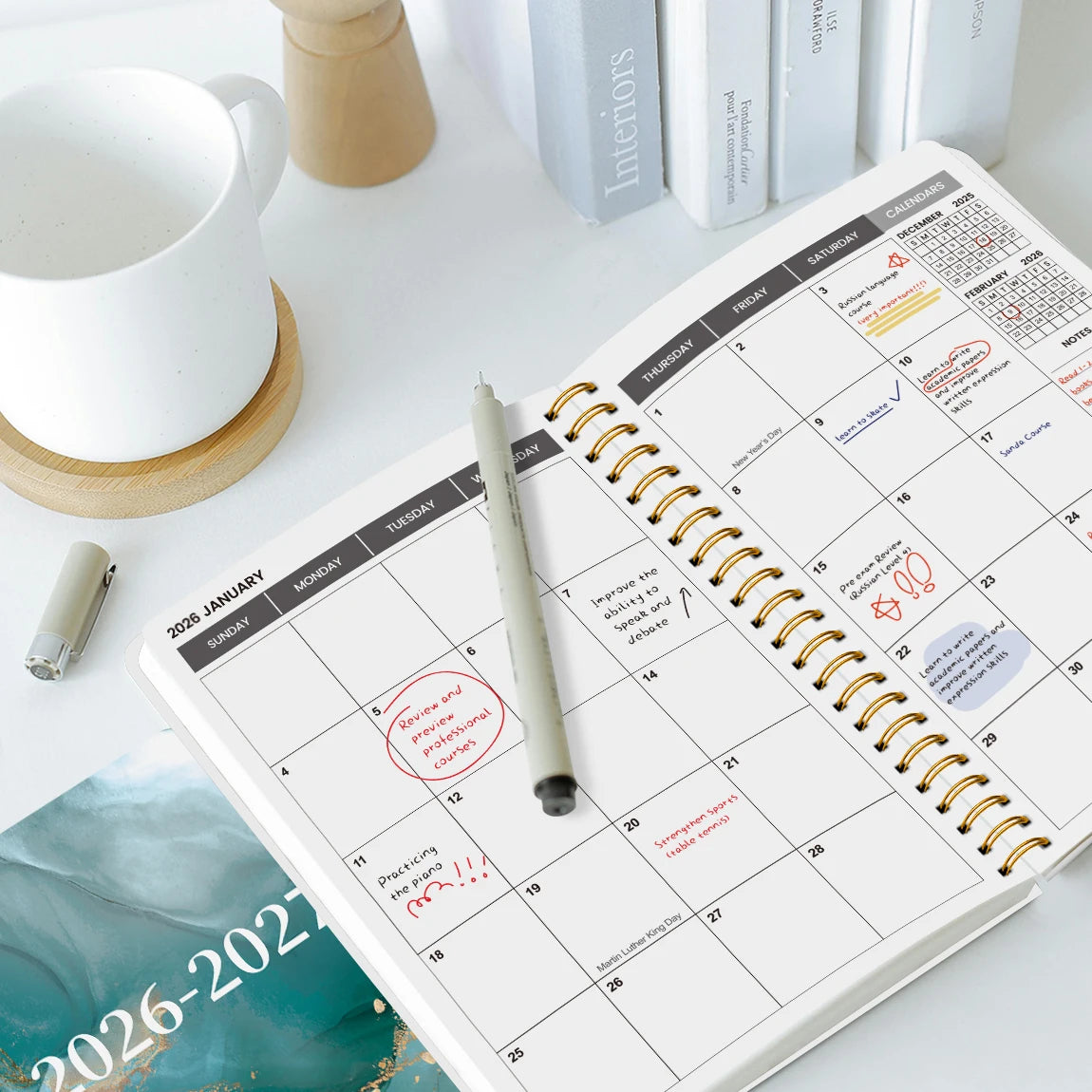 An open A5 weekly and monthly planner showing pages for January 2026 to December 2027 with ruled lines and calendar grids.
