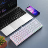 A close-up view of a white 68-key wired RGB gaming keyboard, a smartphone, and a laptop on a gray surface.