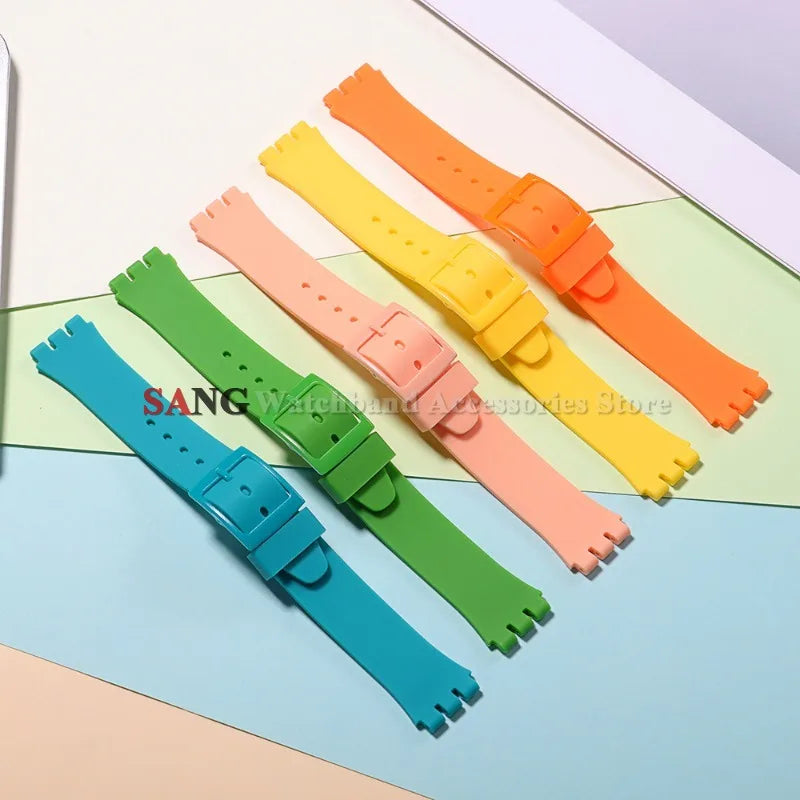 A collection of colorful soft silicone watch straps in various shades including orange, yellow, pink, and green laid out on a
