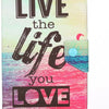 A pink and teal silicone folio case featuring the text LIVE the life you LOVE overlaid on a vibrant sunset sea background.