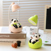 A pink panda-shaped LED desk lamp with a mobile phone holder sits on a white desk next to a laptop.