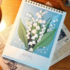 Calendario de escritorio mensual decorativo con ilustración floral en la portada.