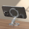 A dark gray foldable dual-sided phone stand with MagSafe compatibility resting on a wooden surface.