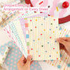 Una hoja de papel de scrapbooking en cuadrícula rosa con puntos y líneas de colores es sostenida por una mano.