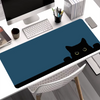 A dark blue cat silhouette mouse pad is placed on a white desk next to a computer monitor and keyboard.