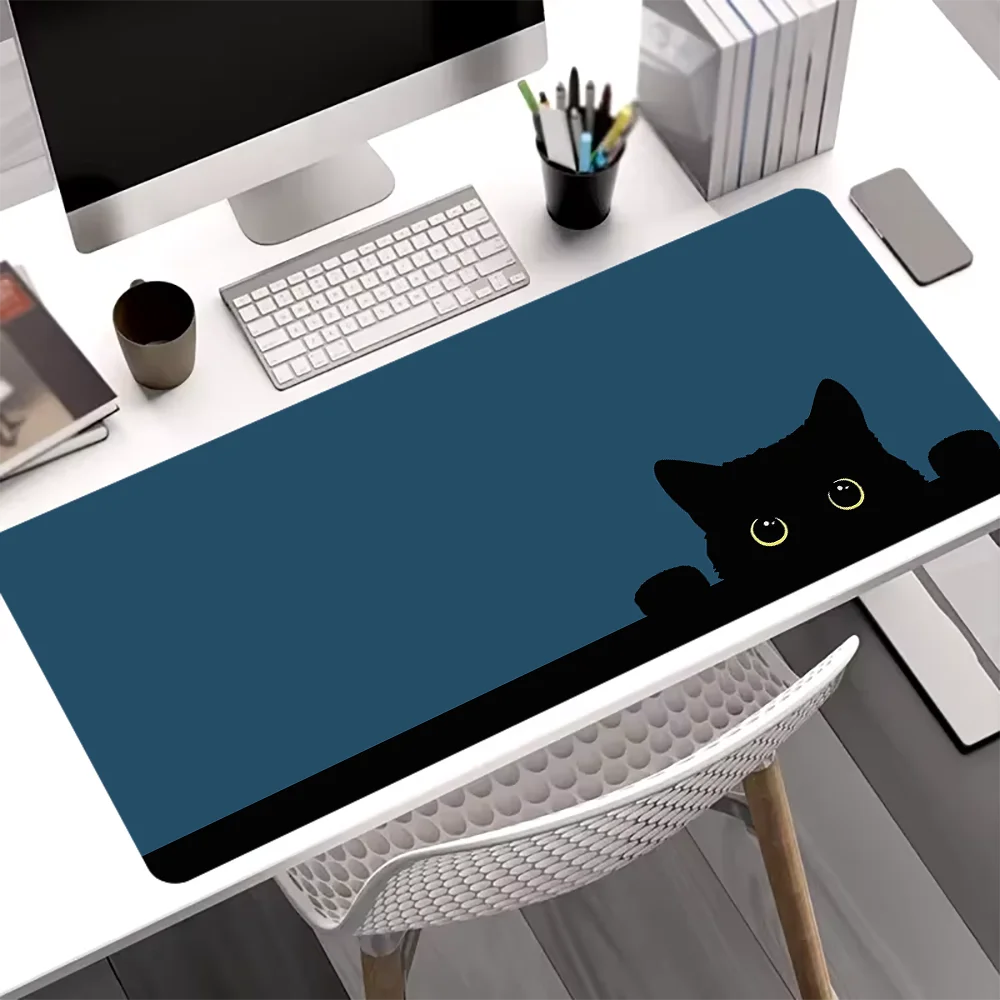 A dark blue cat silhouette mouse pad is placed on a white desk next to a computer monitor and keyboard.