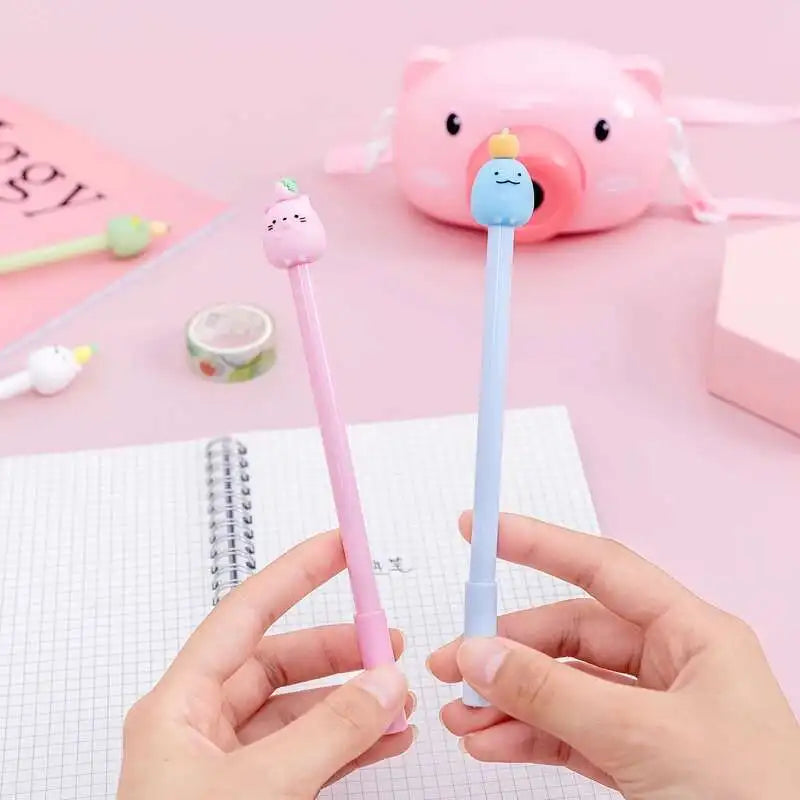 A pair of pink and blue cute cartoon fruit gel pens are held over a white notepad.