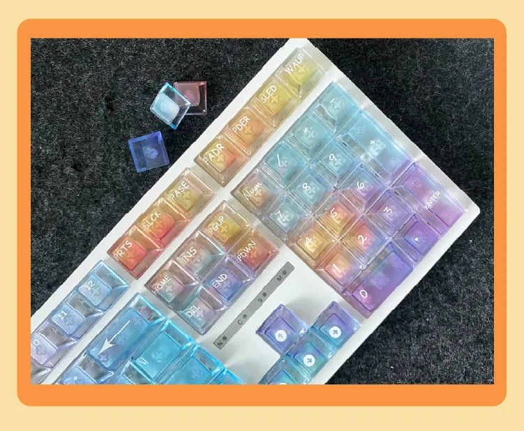 A collection of colorful rainbow shine PC keycaps arranged on a white tray.