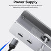 A close-up view of a silver USB-C hub with multiple ports and a power input cable connected.
