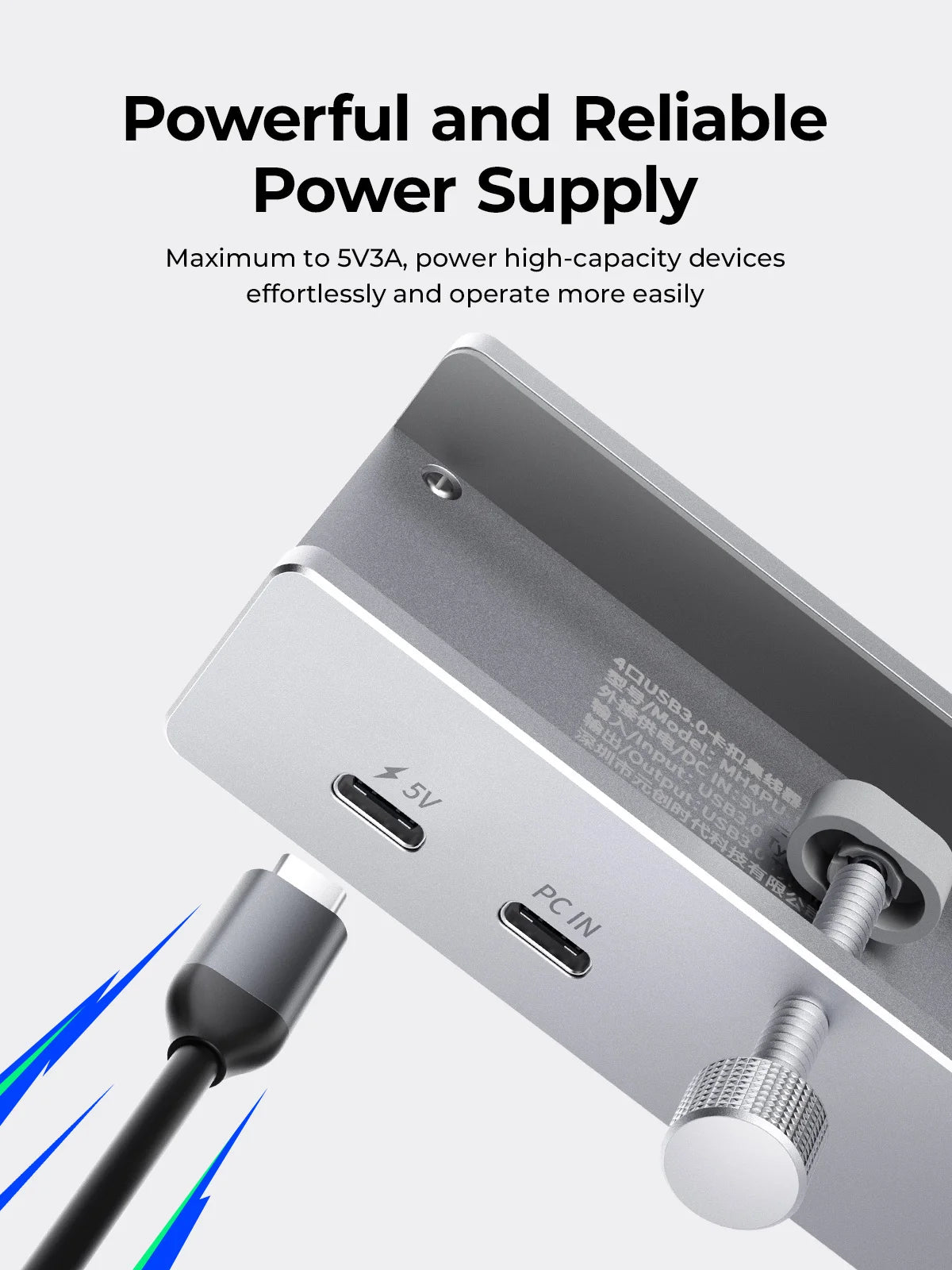 A close-up view of a silver USB-C hub with multiple ports and a power input cable connected.