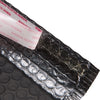 A close-up view of black bubble mailers with a white adhesive label on the edge.