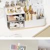 A white desk organizer with two clear drawers holding various cosmetic and stationery products.